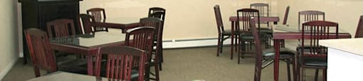 Common area with 5 tables surrounded by chairs. There's a TV on the left.