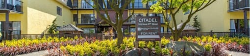 Citadel in North Vancouver, BC Building exterior with vibrant flowerbeds full of greenery and trees
