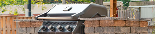 a bbq grill in a backyard with a stone wall
