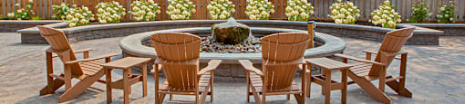 a patio with a fire pit and chairs