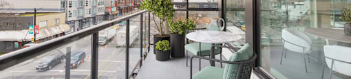 A balcony with a table and chairs overlooking a busy street at 388 Kaslo East Village.