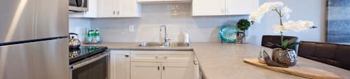 Regency Towers modern kitchen with white cabinetry and stainless steel appliances in St. Catherines, ON