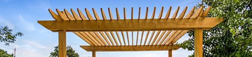 an outdoor bbq area with a wooden pergola on top of a stone patio at Rittenhouse Apartments in Kitchener Ontario