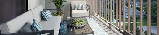 Balcony with outdoor couch, chair, table and large plant at Riverbend Tower Apartments in Chatham, ON
