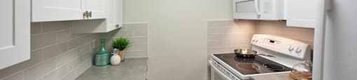 Lord Simcoe Apartments kitchen with full range stove and over-the-range microwave in Niagara Falls, ON