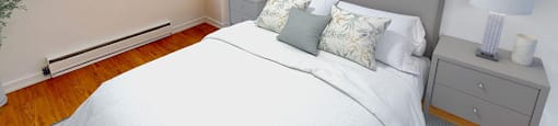 A bedroom with a large bed and a window in a renovated 3 bed 2 bath suite at Somerset Place in London, ON.