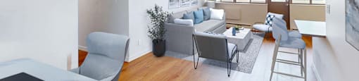 A living room with a grey couch and a grey chair in a renovated 3 bed 2 bath suite at Somerset Place in London, ON.