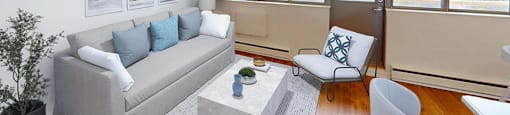 Living area with a couch and chairs next to large windows and a balcony door in a renovated 2 bed 1.5 bath suite at Somerset Place in London, ON.