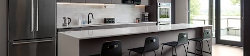 A modern social room with a kitchen area and three chairs at The Ambrosi in Kelowna, BC.