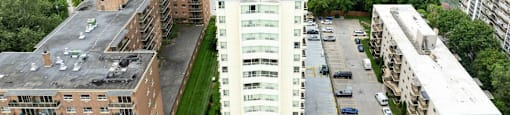 A tall white building is in the center of a parking lot.