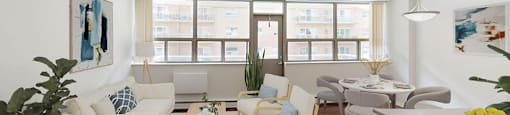 Open concept living area with large windows across the full wall and a balcony door in the middle in a renovated 2 bed 1.5 bath suite at Somerset Place in London, ON.