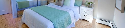 Sunnidale Place Modern bedroom with white covers and light blue blankets and mirrored closet doors in Barrie, ON