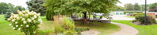 Sunnidale Place garden area with bench seating and patio in background in Barrie, ON