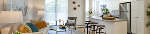 Sunnidale Place Stylish living room with open kitchen facing a balcony and decorated with paintings and sleek decor in Barrie, ON