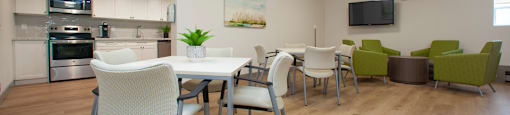 Social room at Sunnidale Place in Barrie, ON featuring kitchen, tables and chairs, comfy lounge seating and flat screen TV
