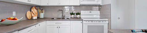 Sunset Towers kitchen with white shaker-style cabinetry, dishwasher, stove and over-the-range microwave in St. Thomas, ON