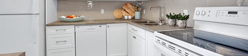 Sunset Towers kitchen with white cabinetry, fridge, dishwasher, stove and over-the-range microwave in St. Thomas, ON