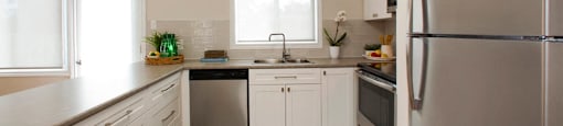 Tamarack Woods Sleek modern kitchen with spotless counters, a fridge, sink, oven and washing machine. Easy view of the outdoor patio through the window and door in Barrie, ON