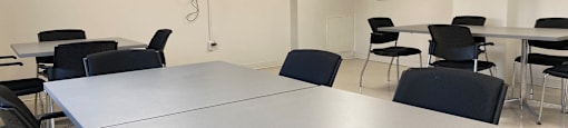 Resident social room with tables and chairs and flatscreen TV at Tarawood Place in Peterborough, ON