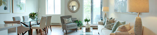 Testa Heights Apartments in Uxbridge, ON Living Room with Dining Room in Foreground featuring patio doors and windows with blinds included