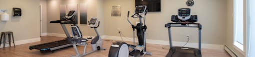 a gym with treadmills and other exercise equipment on a wood floor