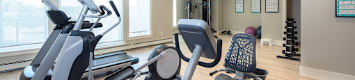 a gym with cardio equipment and windows in a building