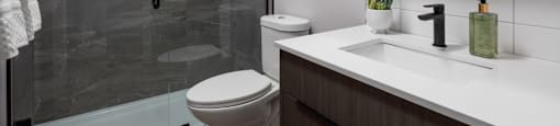 A modern bathroom with a walk-in shower and a toilet at The Ambrosi in Kelowna, BC.