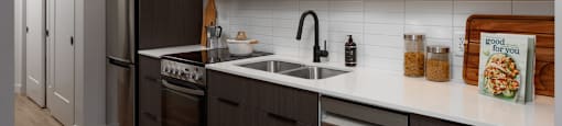 A modern kitchen with dark wood cabinets and stainless steel appliances at The Ambrosi in Kelowna, BC.