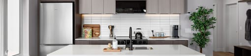 A modern kitchen with a white island and bar stools at The Ambrosi in Kelowna, BC.