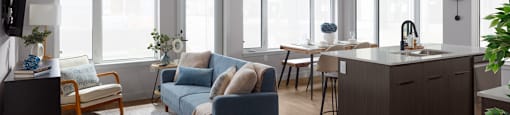 A living room with a blue couch and wooden floors at The Ambrosi in Kelowna, BC.
