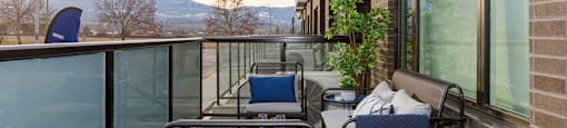 A balcony with a table and chairs overlooking a mountain range at The Ambrosi in Kelowna, BC.