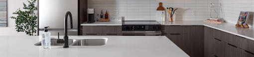 A modern kitchen with a white countertop and brown cabinets at The Ambrosi in Kelowna, BC.