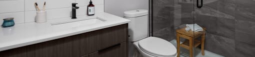 A bathroom with a toilet, sink, and a shower at The Ambrosi in Kelowna, BC.