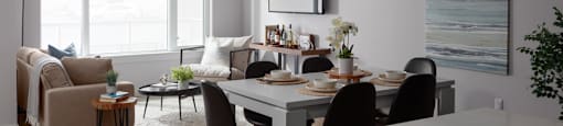 A modern dining room with a white table and black chairs at The Ambrosi in Kelowna, BC.