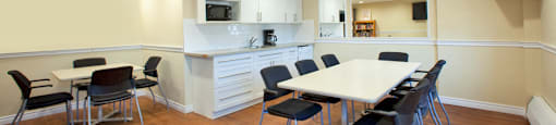 Trillium Apartments social room with kitchenette and tables and chairs in Cobourg, ON