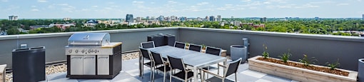 A rooftop patio with a BBQ grill and a table and chairs at Trio on Belmont in Kitchener, ON