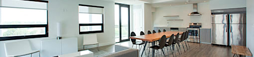 Trio on Belmont large social room with couch seating area, long table with chairs, and kitchen in Kitchener, ON