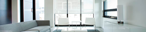 Lounge area with grey couch and white table in the social room located in Building C at Trio on Belmont in Kitchener, ON