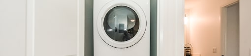In-suite laundry with a white stacked washer and dryer in a 1 bed 1 bath variation B in building A at Trio on Belmont in Kitchener, ON
