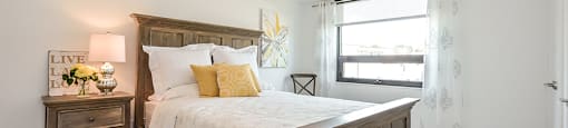 2nd bedroom with a large bed with wooden frame and window in a 2 bed + den 2 bath variation E in building A at Trio on Belmont in Kitchener, ON