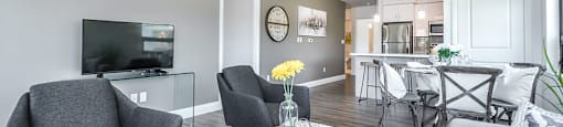 Open-concept living and dining area, looking towards kitchen, in a 2 bed + den 2 bath variation E in building A at Trio on Belmont in Kitchener, ON