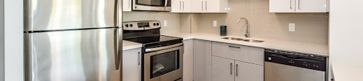 Kitchen with stainless steel appliances and white cabinets in a 2 bed + den 2 bath variation E in building A at Trio on Belmont in Kitchener, ON