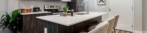 an open kitchen with an island and chairs at Vale Station Apartments in Waterloo ON