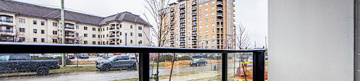 Ground floor patio with glass railing overlooking the street in a 2 bedroom 2 bathroom variation C layout at Vale Station Apartments in Waterloo, Ontario