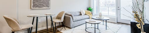 Dining and living area with a two-seater dining table and chairs, couch and two round coffee tables in a 2 bedroom 2 bathroom variation C layout at Vale Station Apartments in Waterloo, Ontario