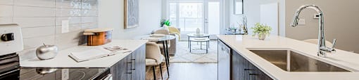 A modern kitchen with dark wood-look lower and white upper cabinets and stainless steel appliances in a 2 bedroom 2 bathroom variation C layout at Vale Station Apartments in Waterloo, Ontario
