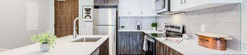 A modern kitchen with wood-look lower and white upper cabinets and a white countertop in a 2 bedroom 2 bathroom variation C layout at Vale Station Apartments in Waterloo, Ontario
