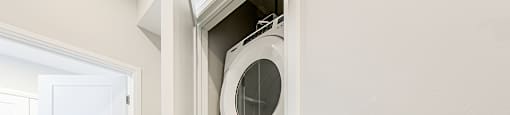 Laundry closet with stacked white washer and dryer in a 2 bedroom 2 bathroom variation C layout at Vale Station Apartments in Waterloo, Ontario