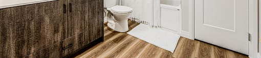 Ensuite bathroom with a large soaker tub with a tiled surround, large vanity, white toilet and linen closet at Vale Station Apartments in Waterloo, Ontario