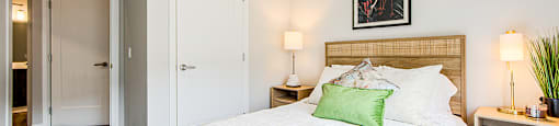 Second bedroom with a large bed and a painting above it in a 2 bedroom 2 bathroom variation C layout at Vale Station Apartments in Waterloo, Ontario